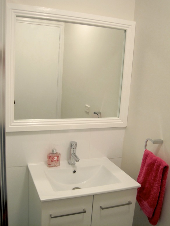 bathroom shot with white framed mirror above sink